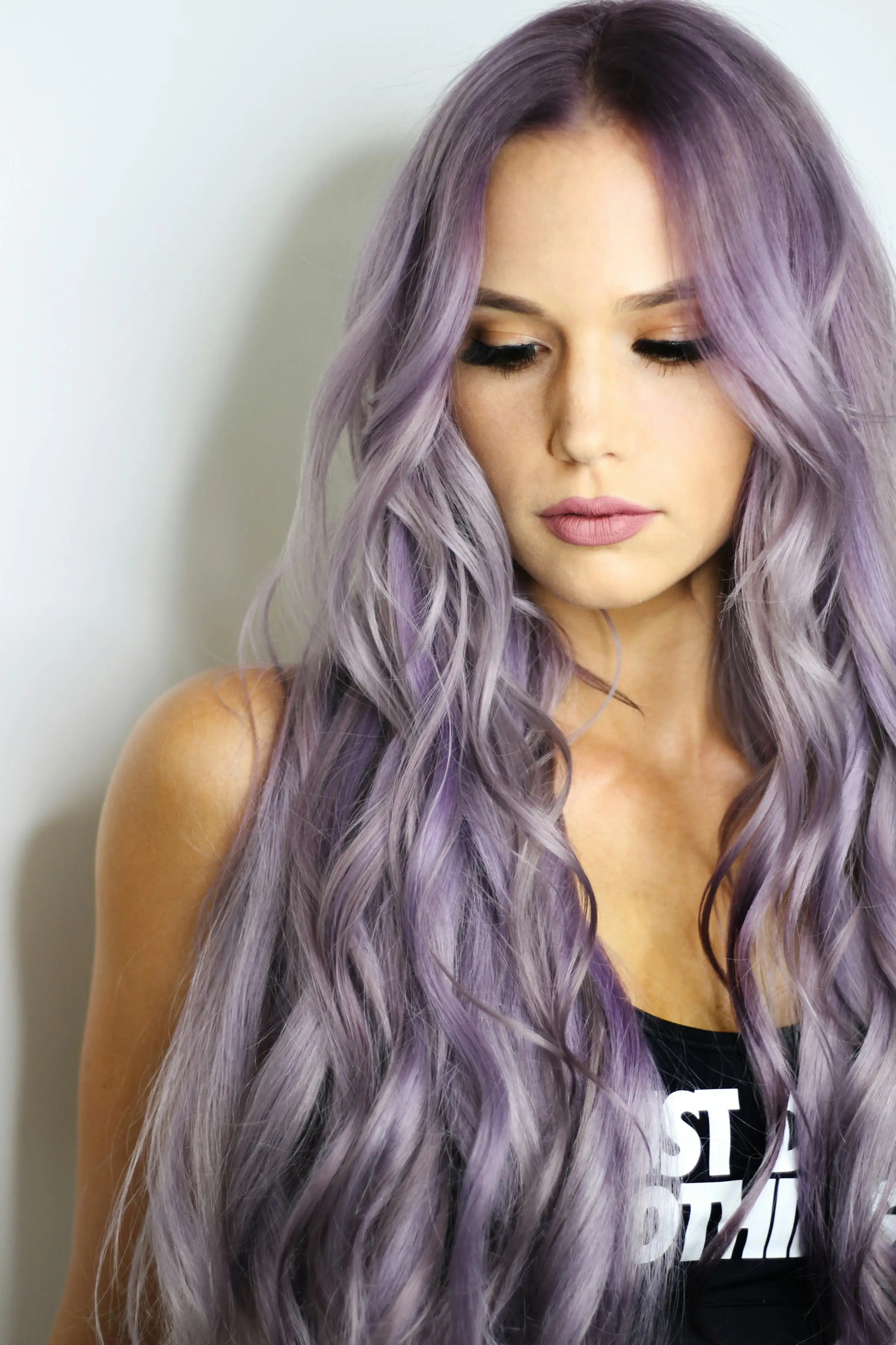A woman with very long, wavy lilac hair falling over one shoulder