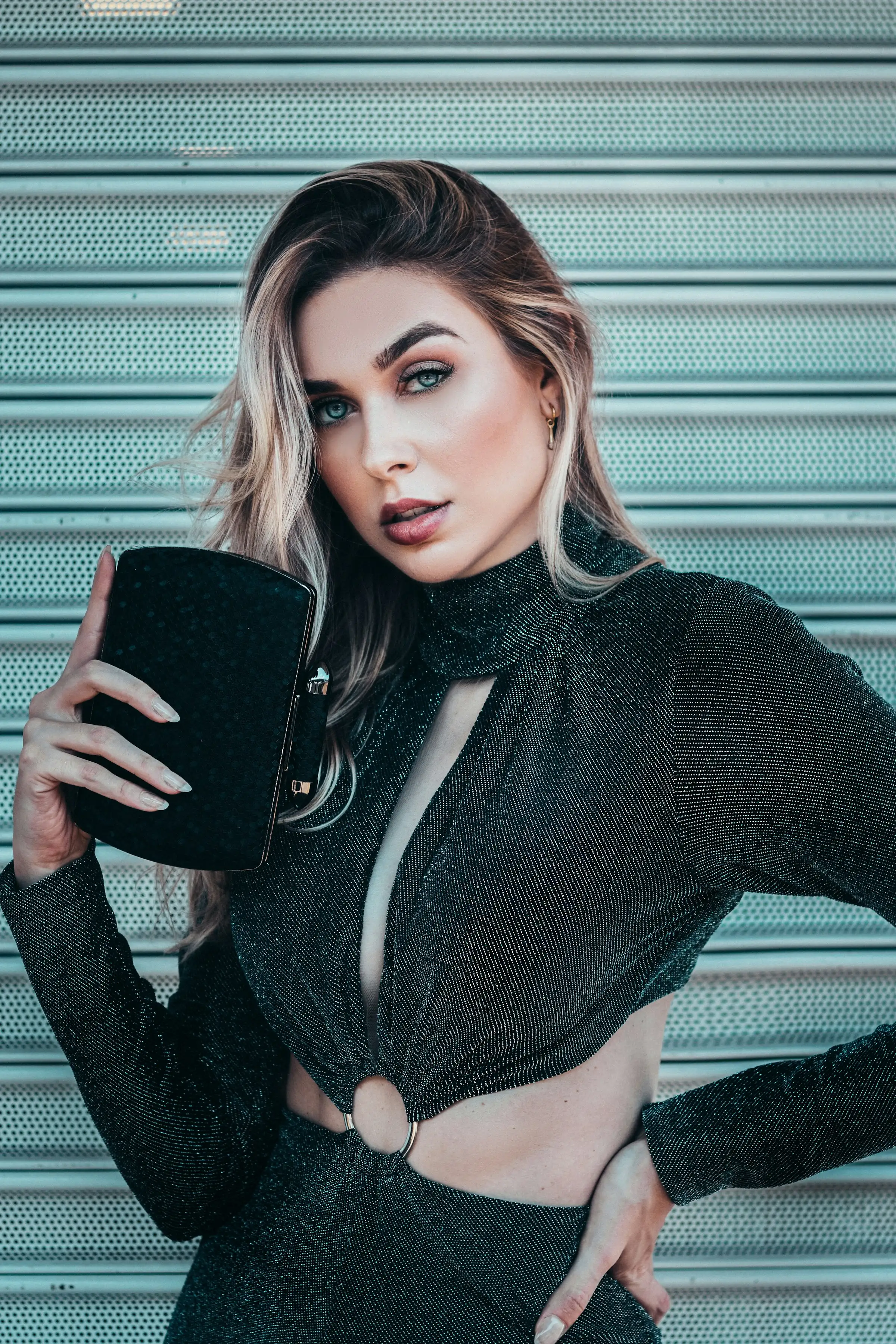 Long hair with blonde-tipped ends, against a teal roller door